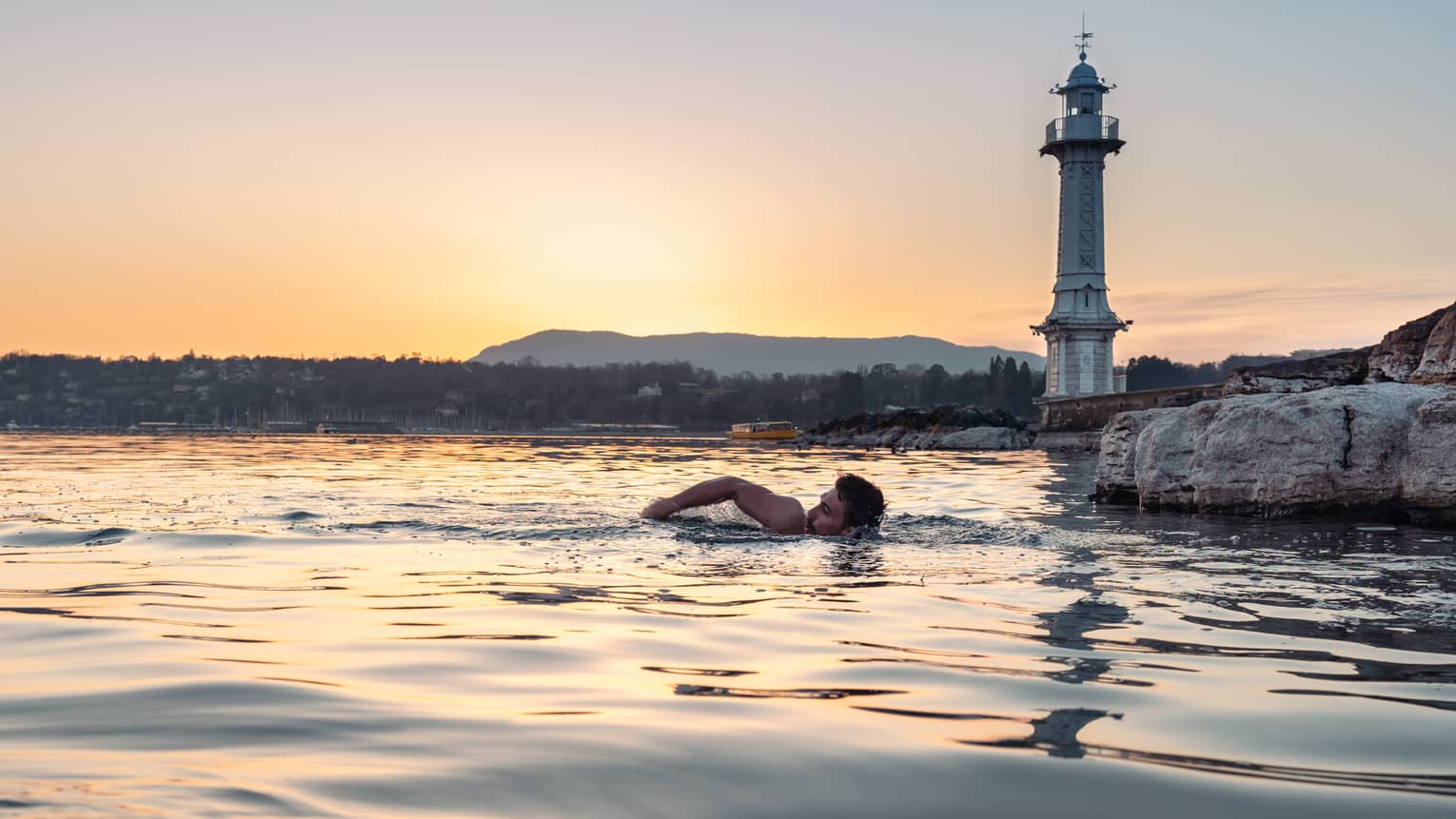 Person swimming in Lake Geneva at sunset