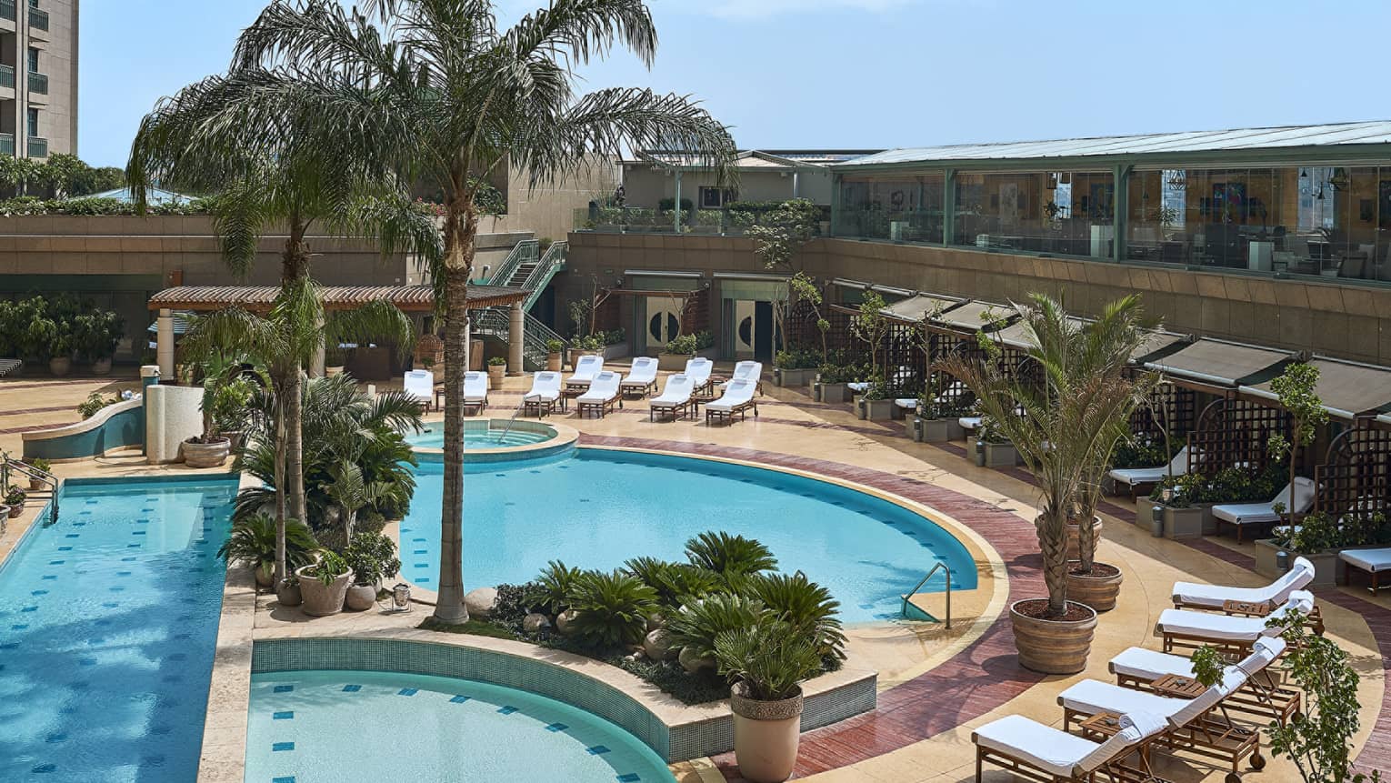 Aerial view of blue-water circular pool with lounge chairs and palm trees