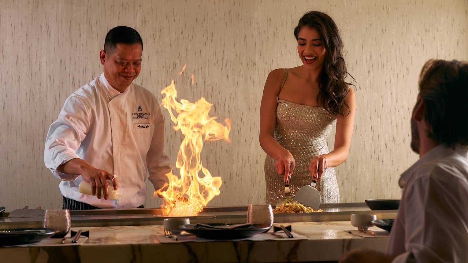 Chef demonstrates how to make a dish side by side with guest in open show kitchen