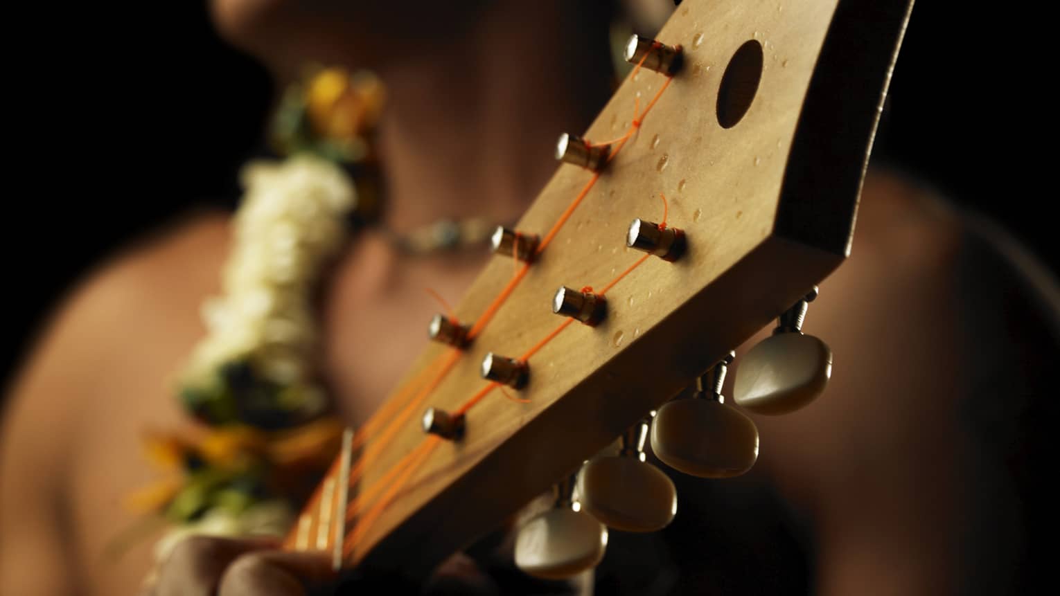 Close-up of native man wearing a lei and playing ukulele 