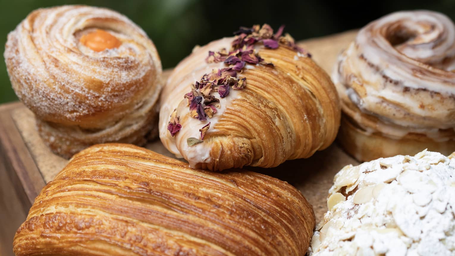 Five different pastries with toppings on an outdoor table.