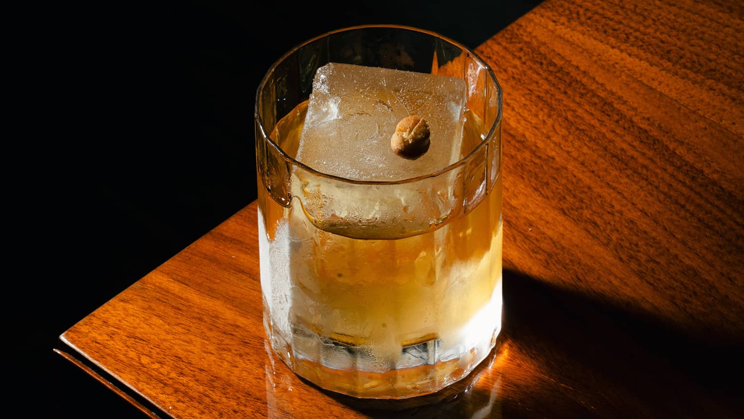 Cocktail in a rocks glass with one large ice cube