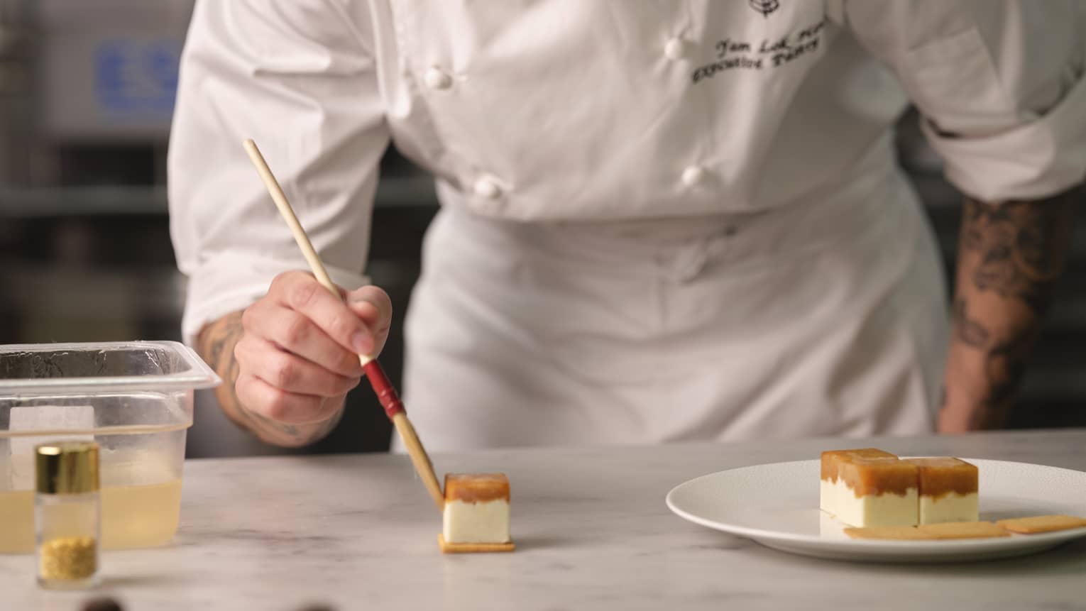 A chef paints small cakes using a paintbrush.
