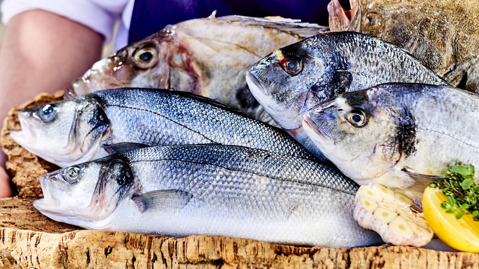 Four whole fish on wood platter with lemon