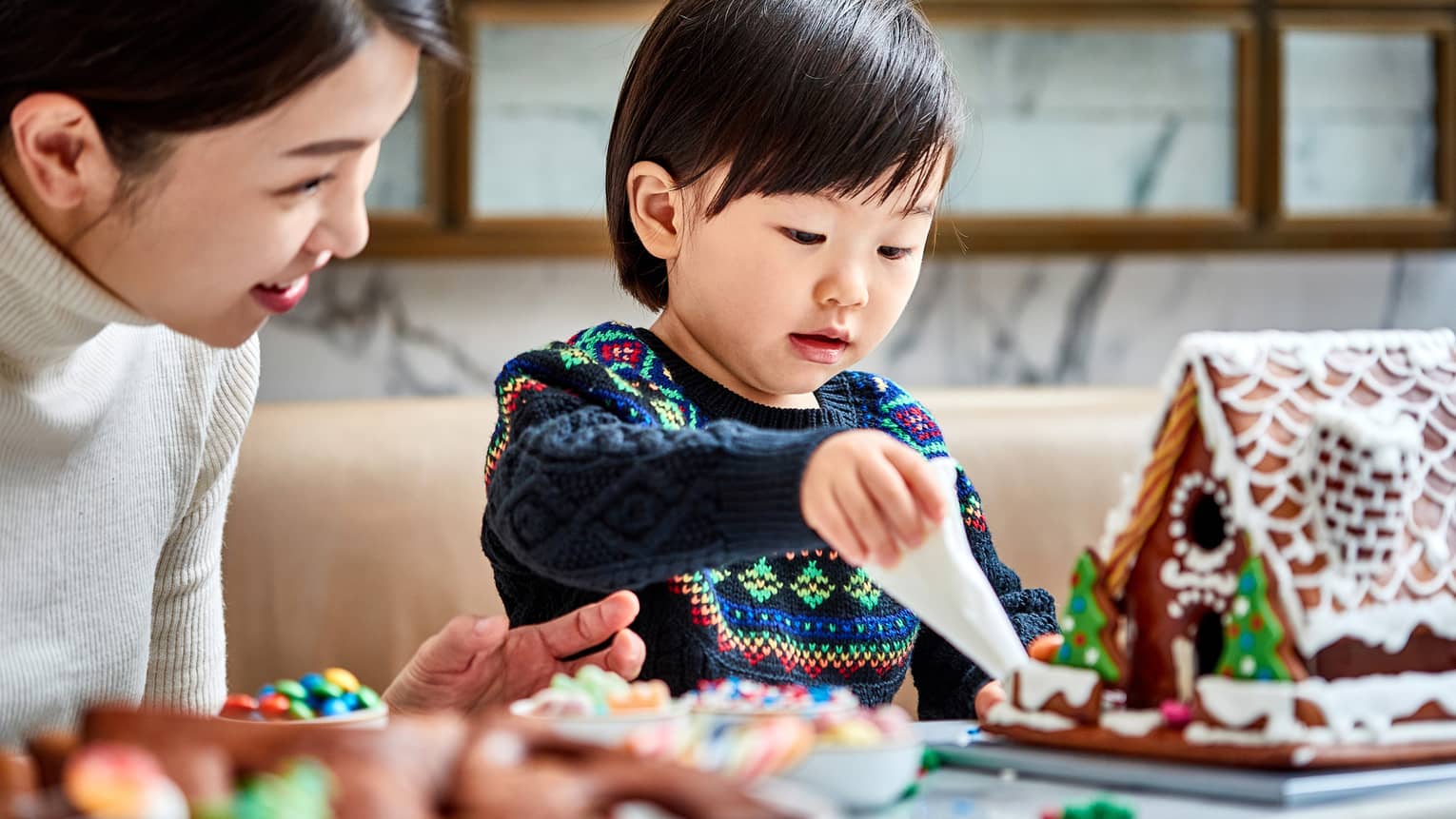 A mother and child make gingerbread houses together
