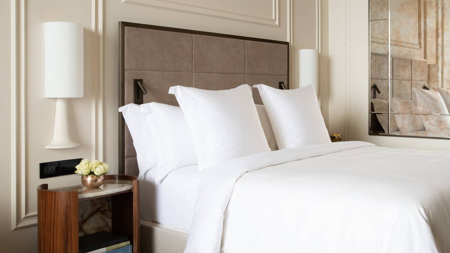 White king bed with taupe head board and white walls with molding detail