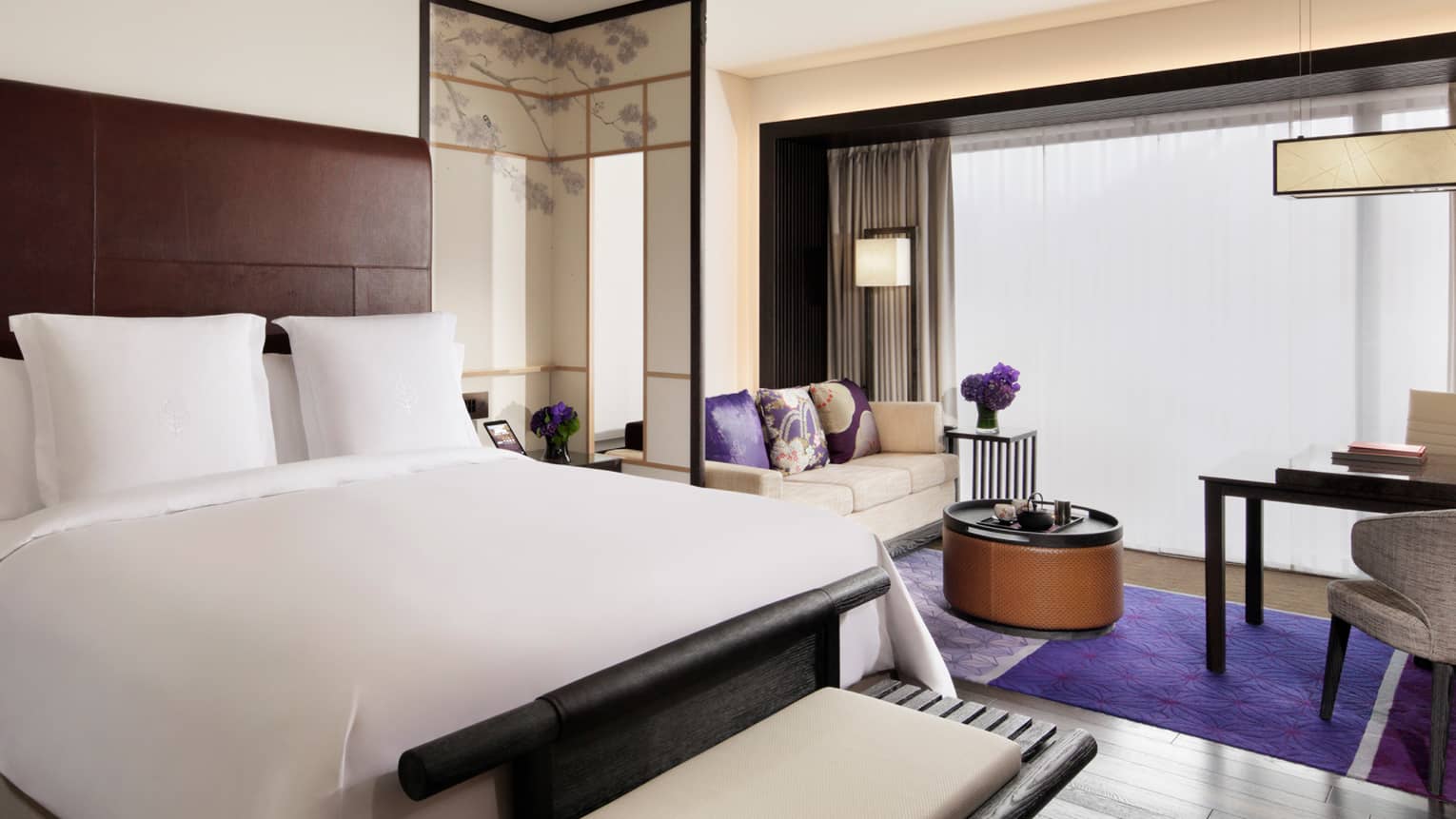 Premier guest room with king bed, work desk with two chairs, sofa, coffee table and modern decor with purple accents and flowers,Guest room with king bed, work desk with two chairs, sofa, coffee table and modern décor with purple accents and flowers