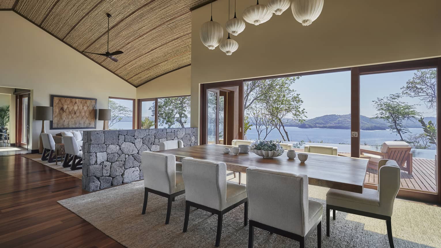 Dining table under modern white lights, stone wall to seating area