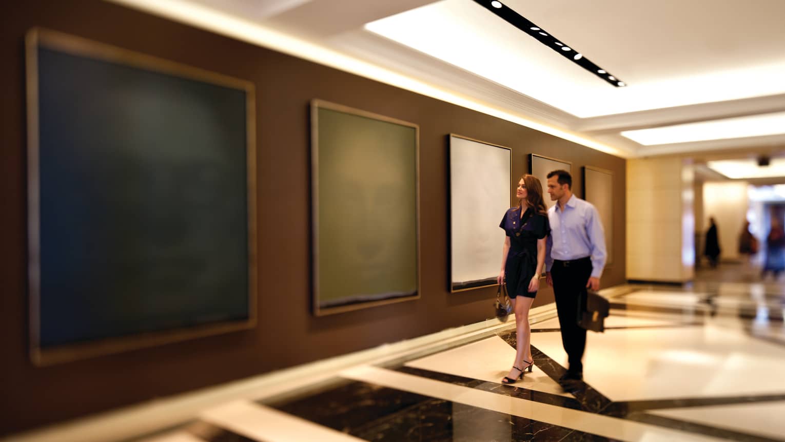 A man and woman walking through an art gallery.