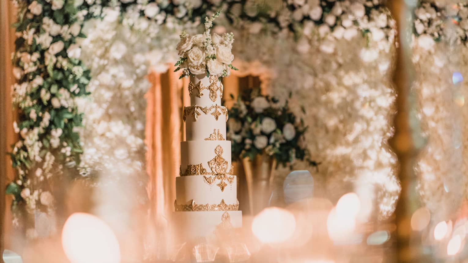 Wedding cake with multiple layers and flowers surrounding it.