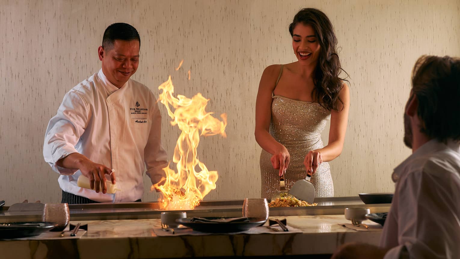 Chef demonstrates how to make a dish side by side with guest in open show kitchen