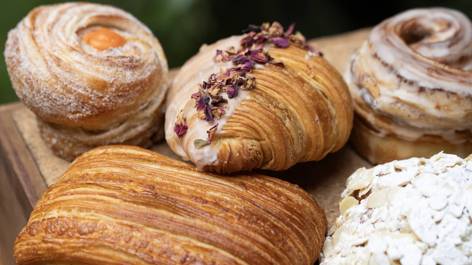 Five different pastries with toppings on an outdoor table.