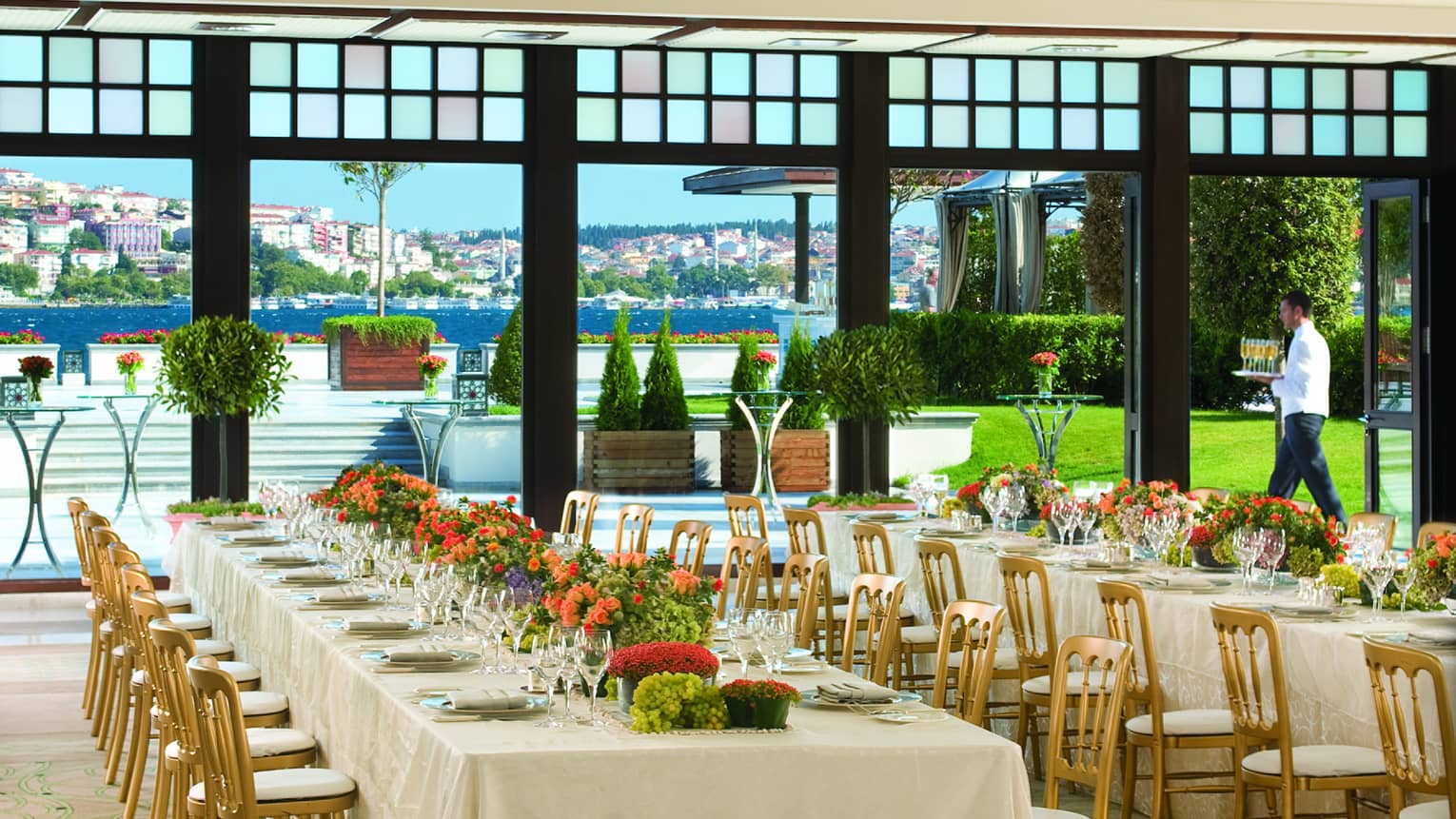 Bosphorus Ballroom long banquet tables with gold chairs under chandeliers, near open wall to terrace