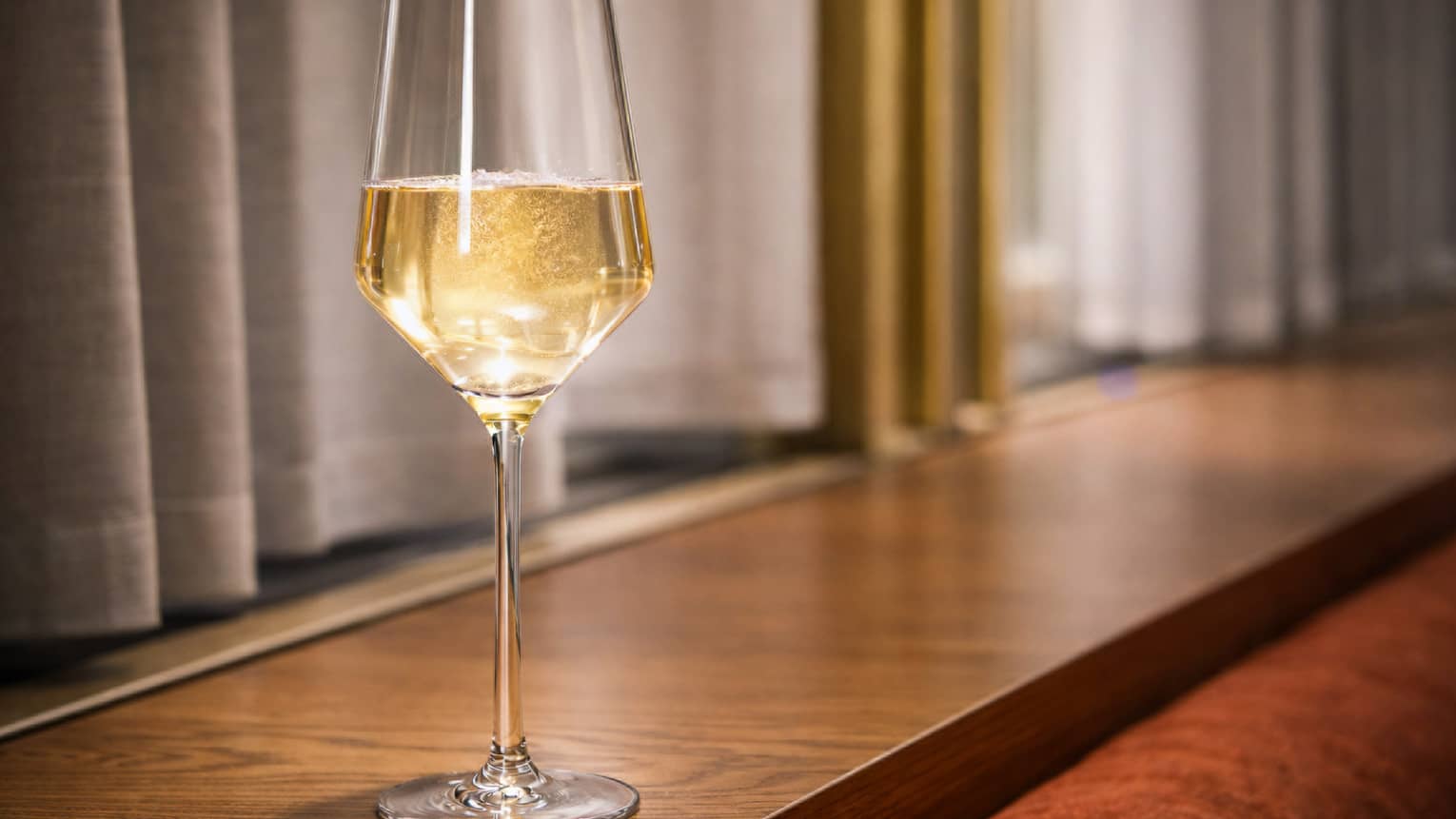 A slender, clear stemmed glass of honey-coloured cocktail