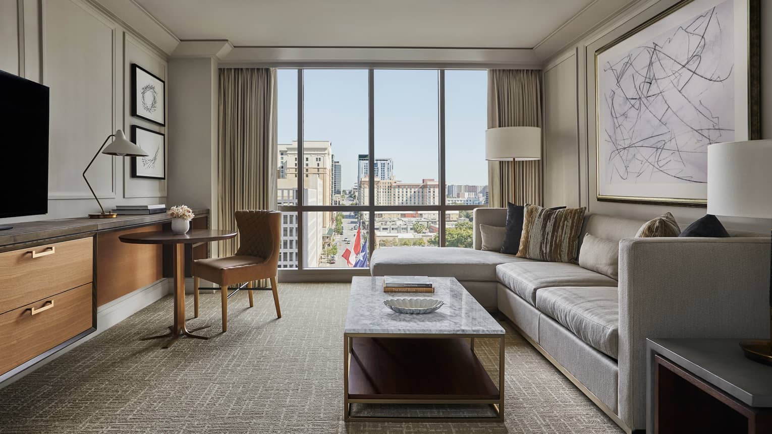 City View Suite, L-shaped sofa, marble coffee table with books, dresser, dining table, large window