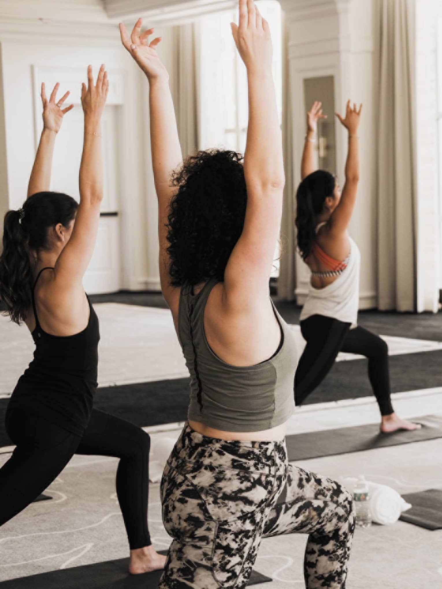 A group of women doing yoga in a well lit room.