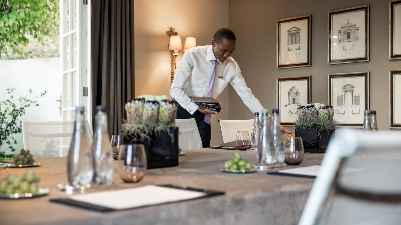 Man in dress shirt and tie sets menu on conference table