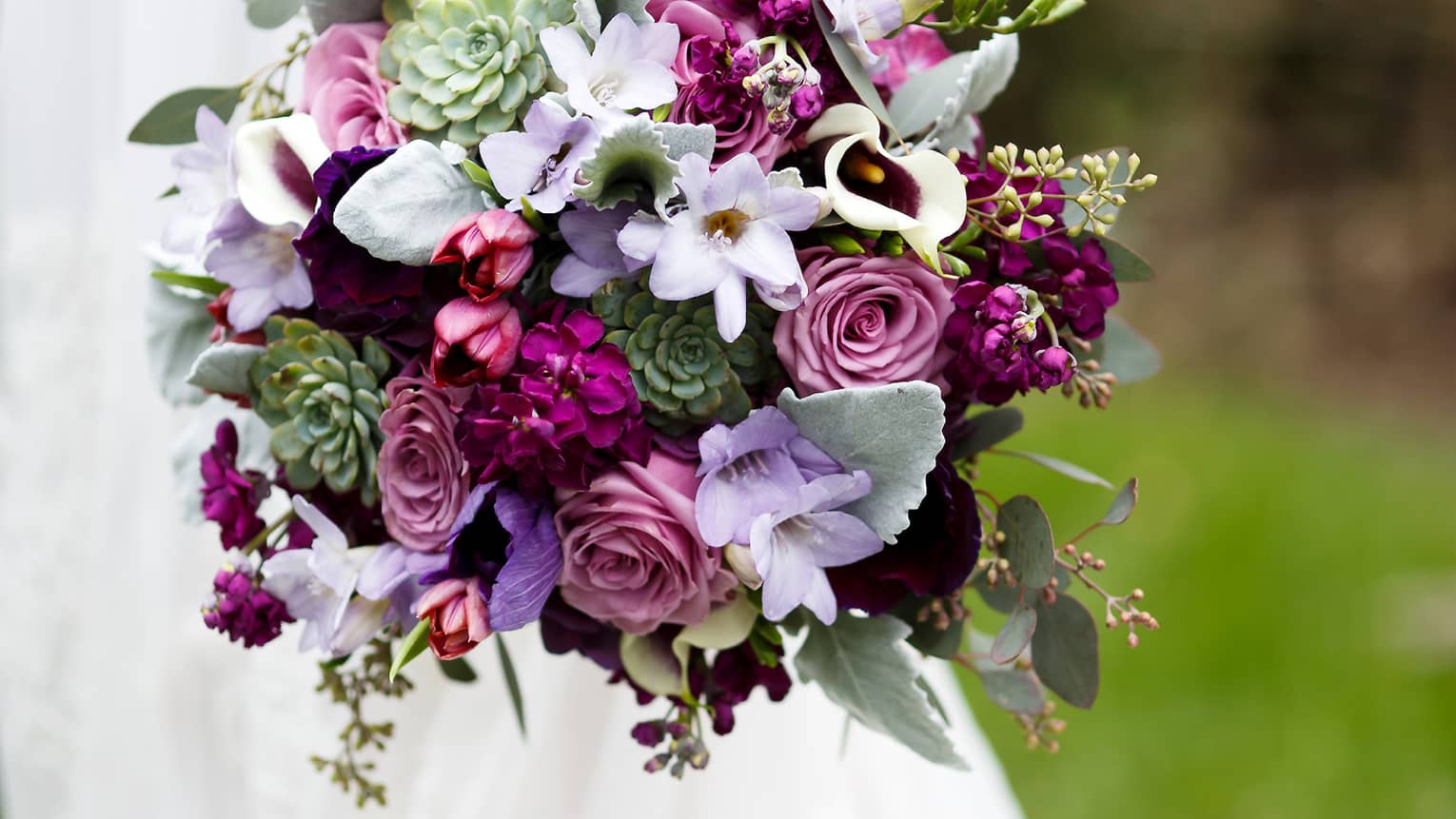 Bride holding floral wedding bouquet with purple flowers