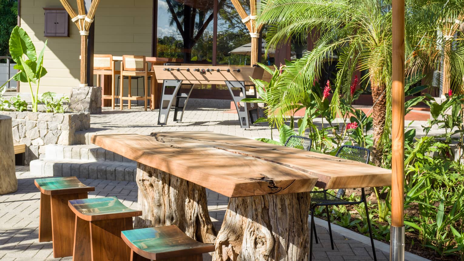 A wooden table surrounded by green palm trees.