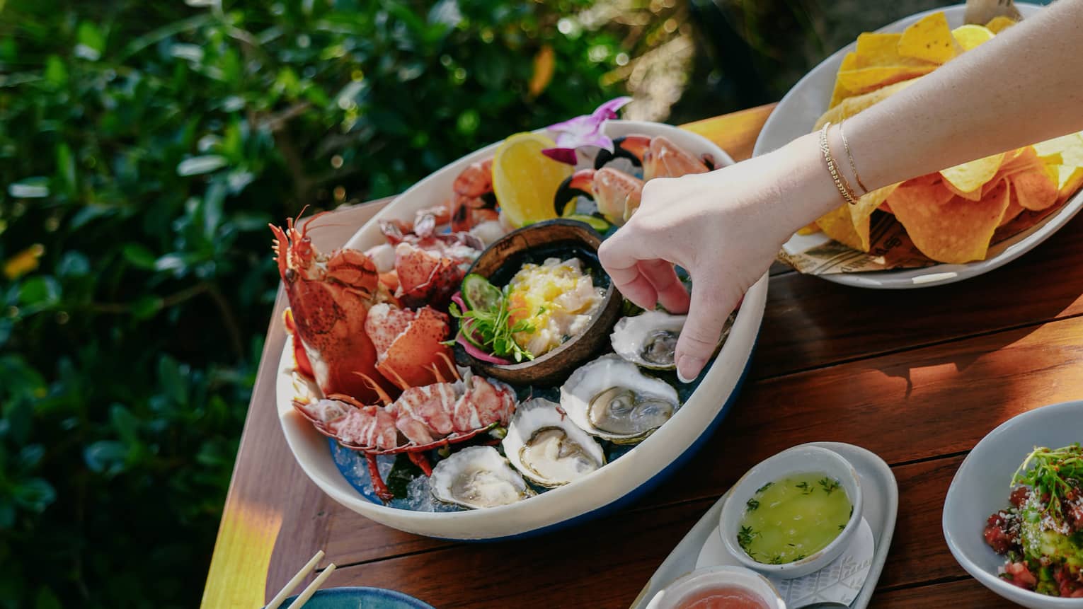 Outdoor table filled with various plates of food, including a large bowl of fresh seafood