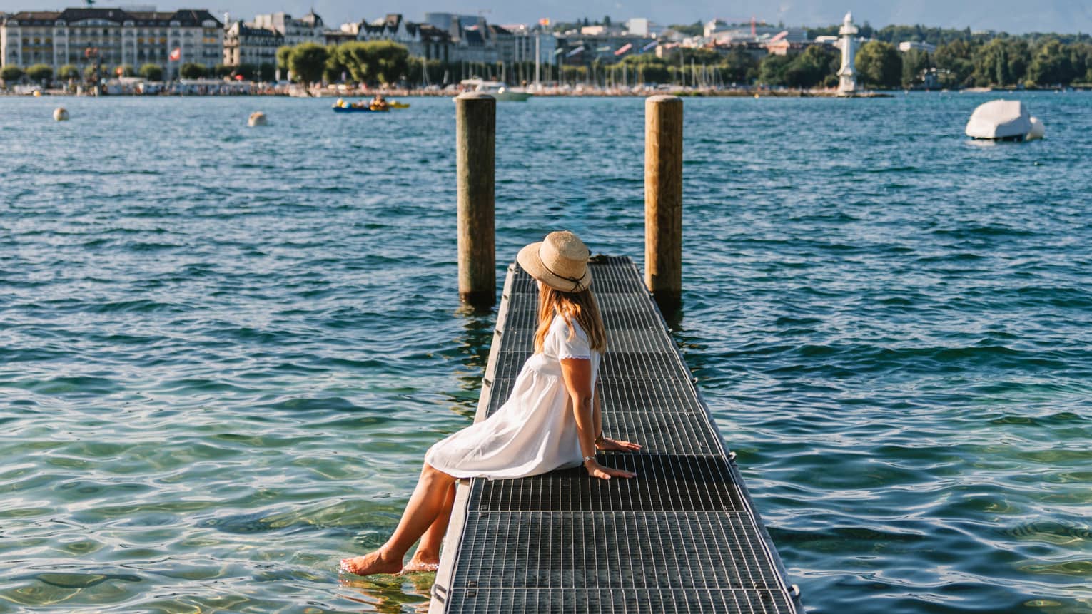 Child sitting on a narrow metal dock leading to two pylons in calm lake