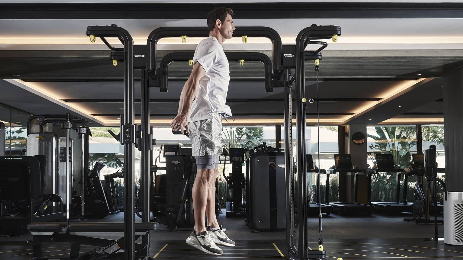 Man in athletic wear jumping vertically beside workout equipment in gym