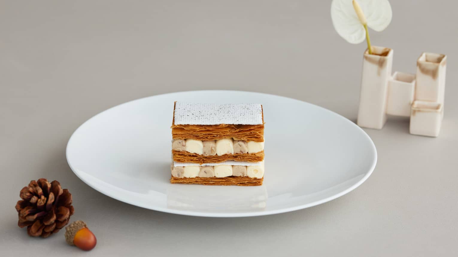 ,A flaky layered pastry filled with dollops of cream on a white plate