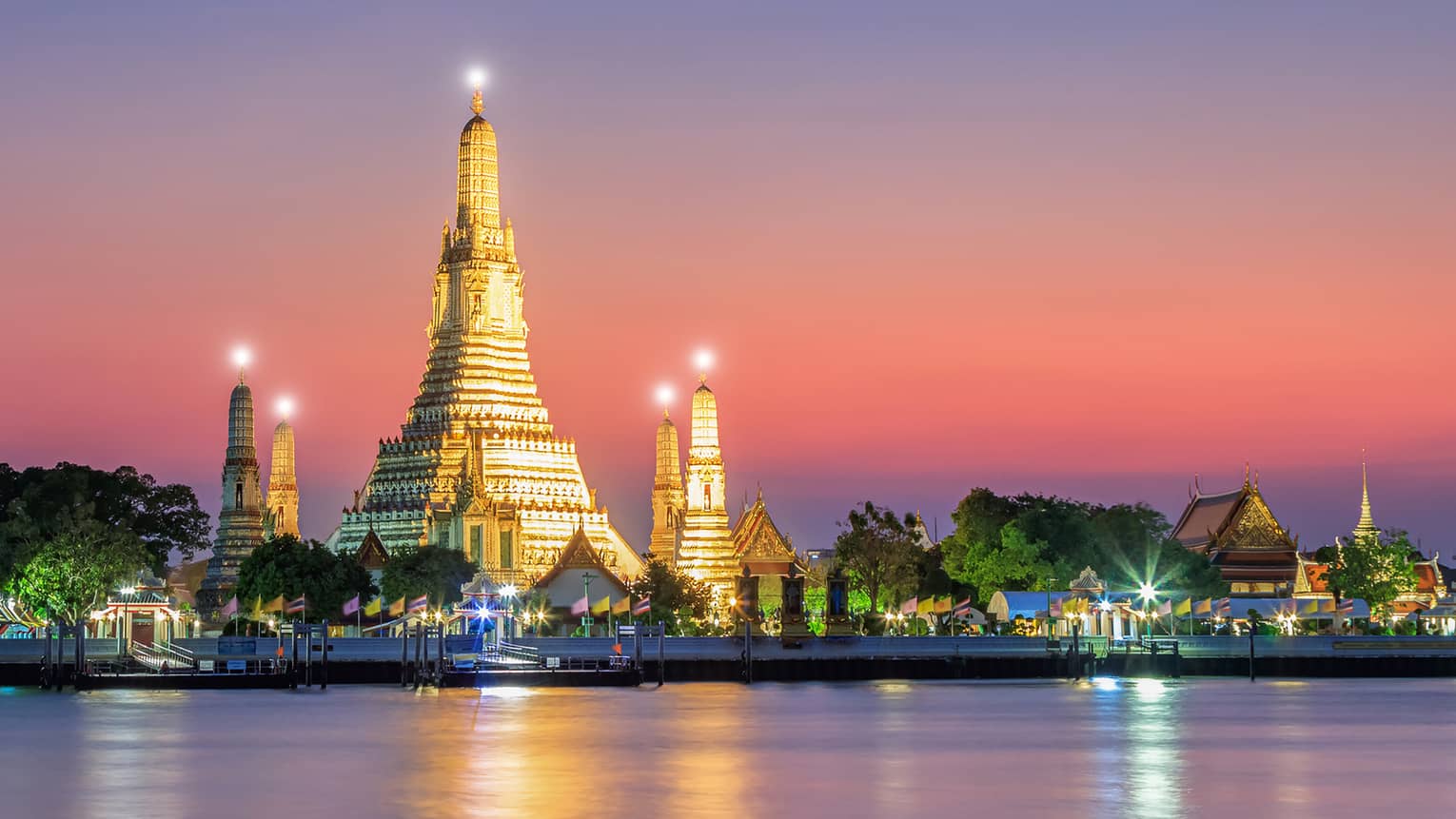 A large structure covered in lights on the shore of water.