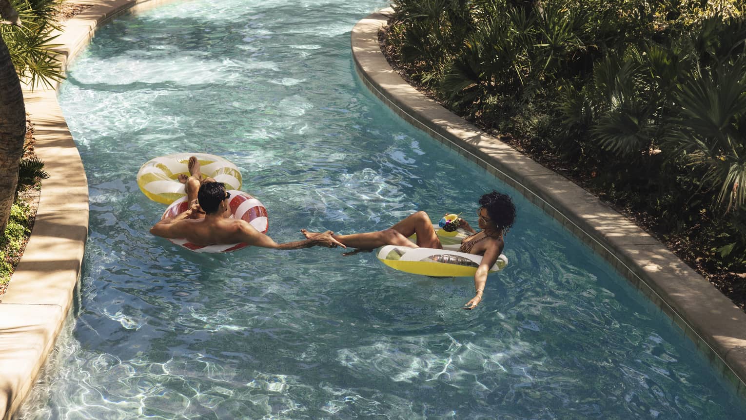 Man and woman float in a lazy river at luxury resort