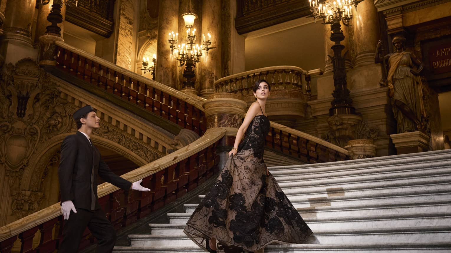 A woman in ballgown ascends grand staircase of opera