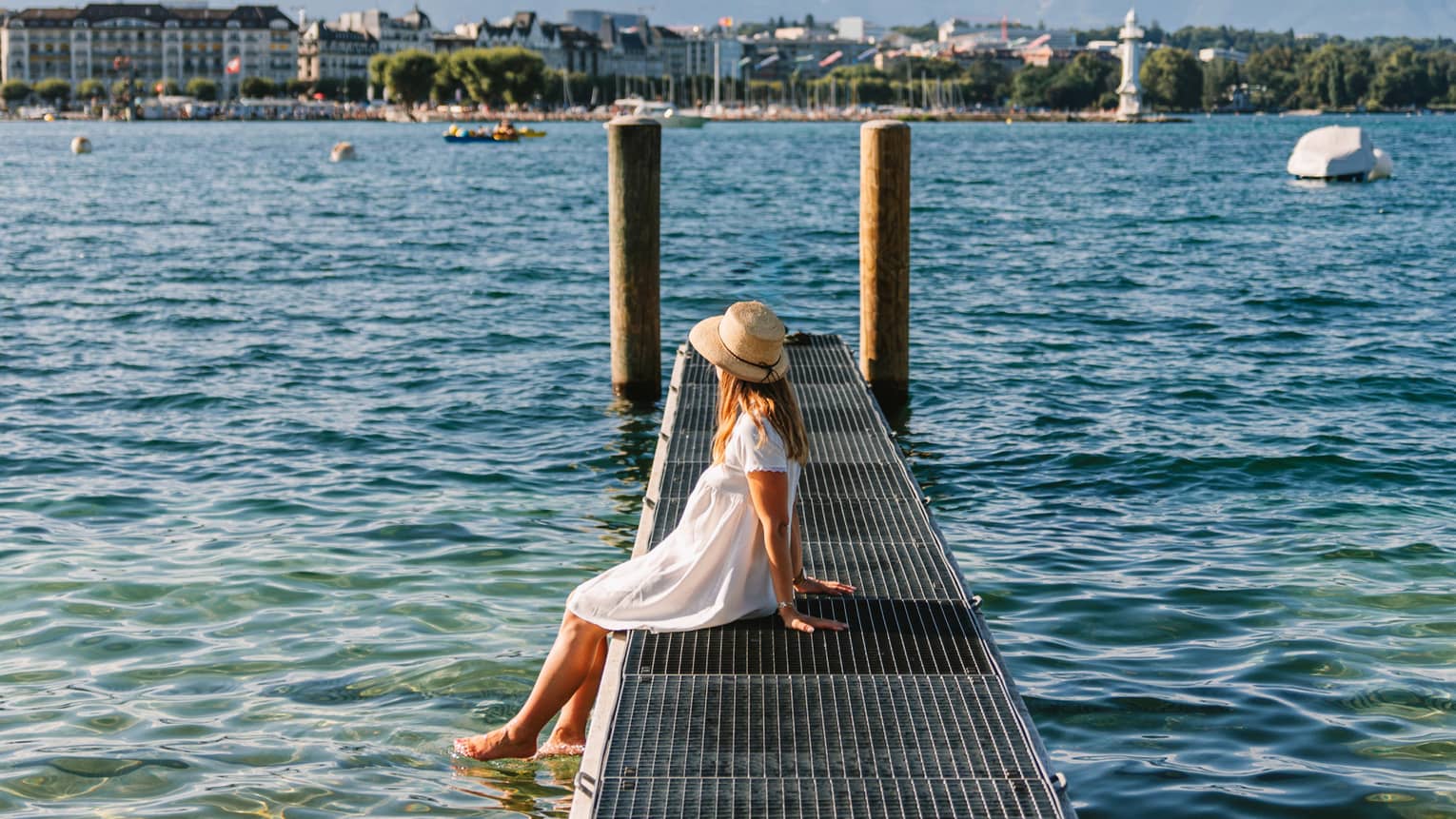 Child sitting on a narrow metal dock leading to two pylons in calm lake