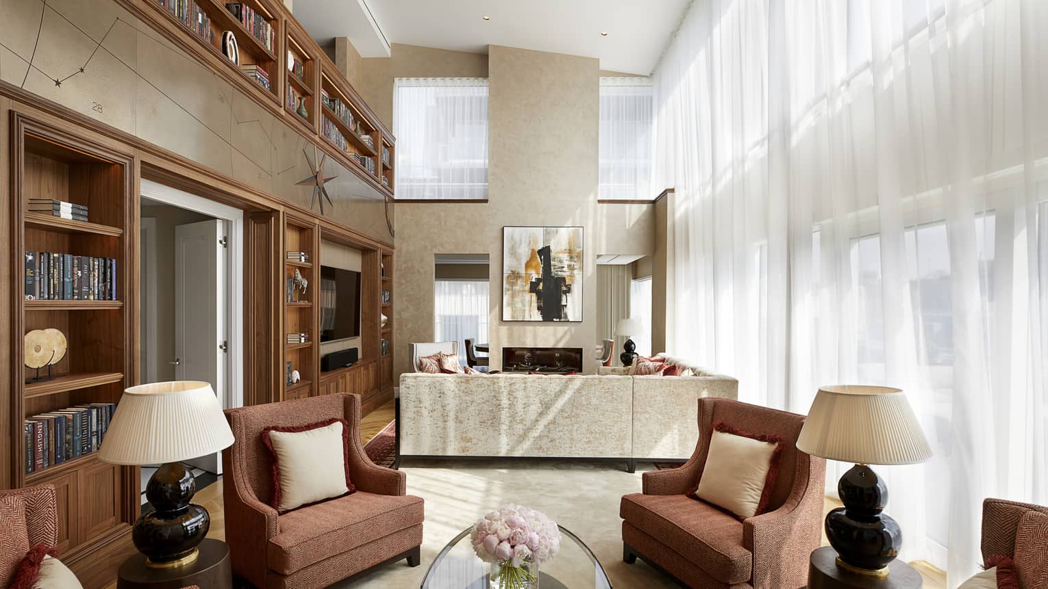 Armchairs, table and lamps under high loft ceilings in front of seating area, sofa