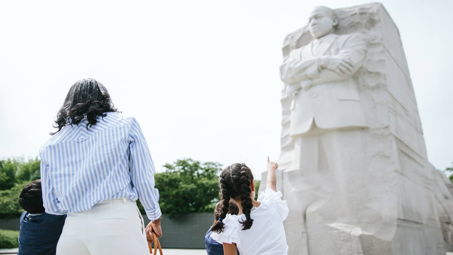 A woman and three children looking at the Martin Luther King, Jr. Memorial on a sunny day.