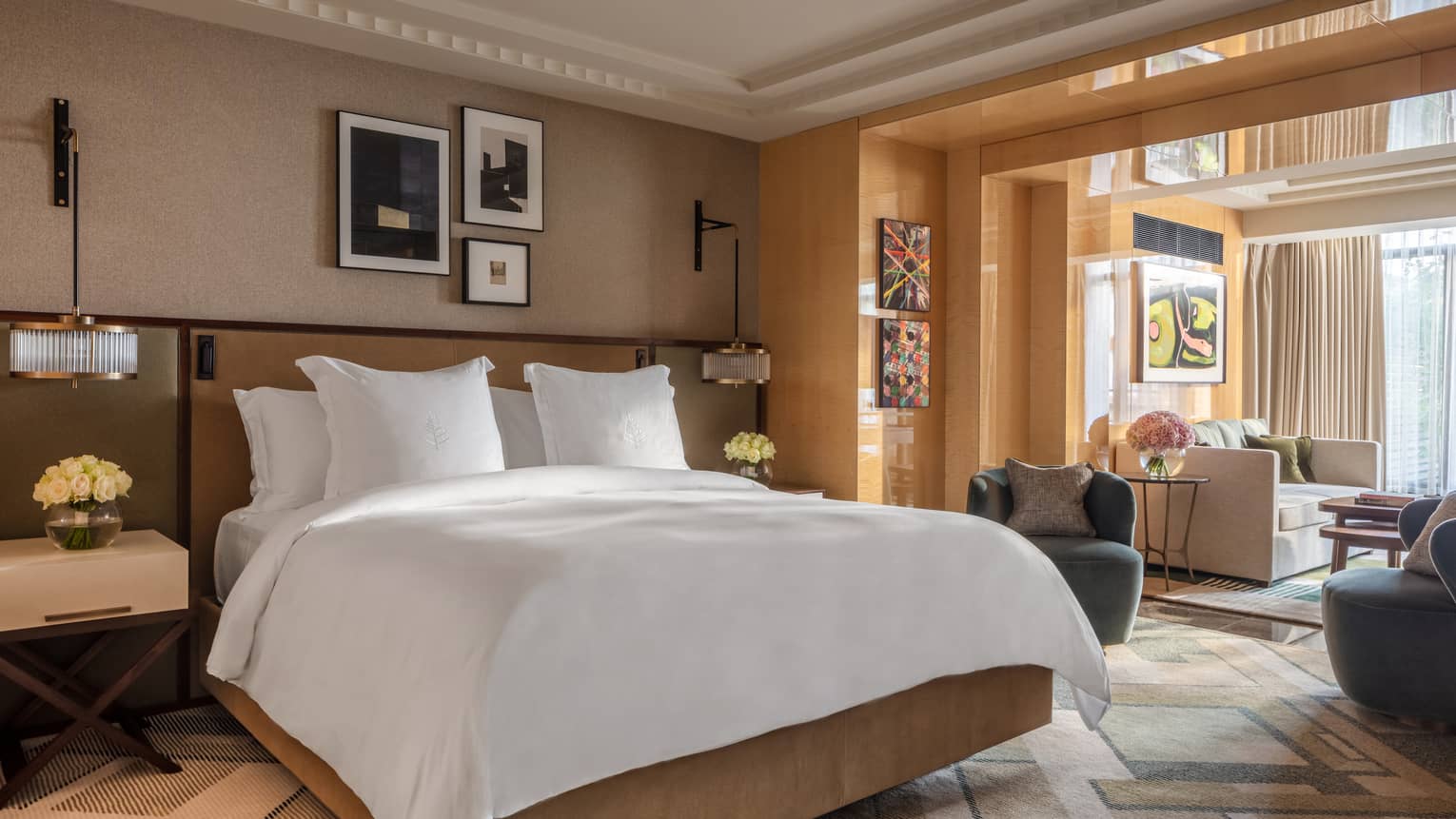 White bed against tan wall with photo gallery and view of living room
