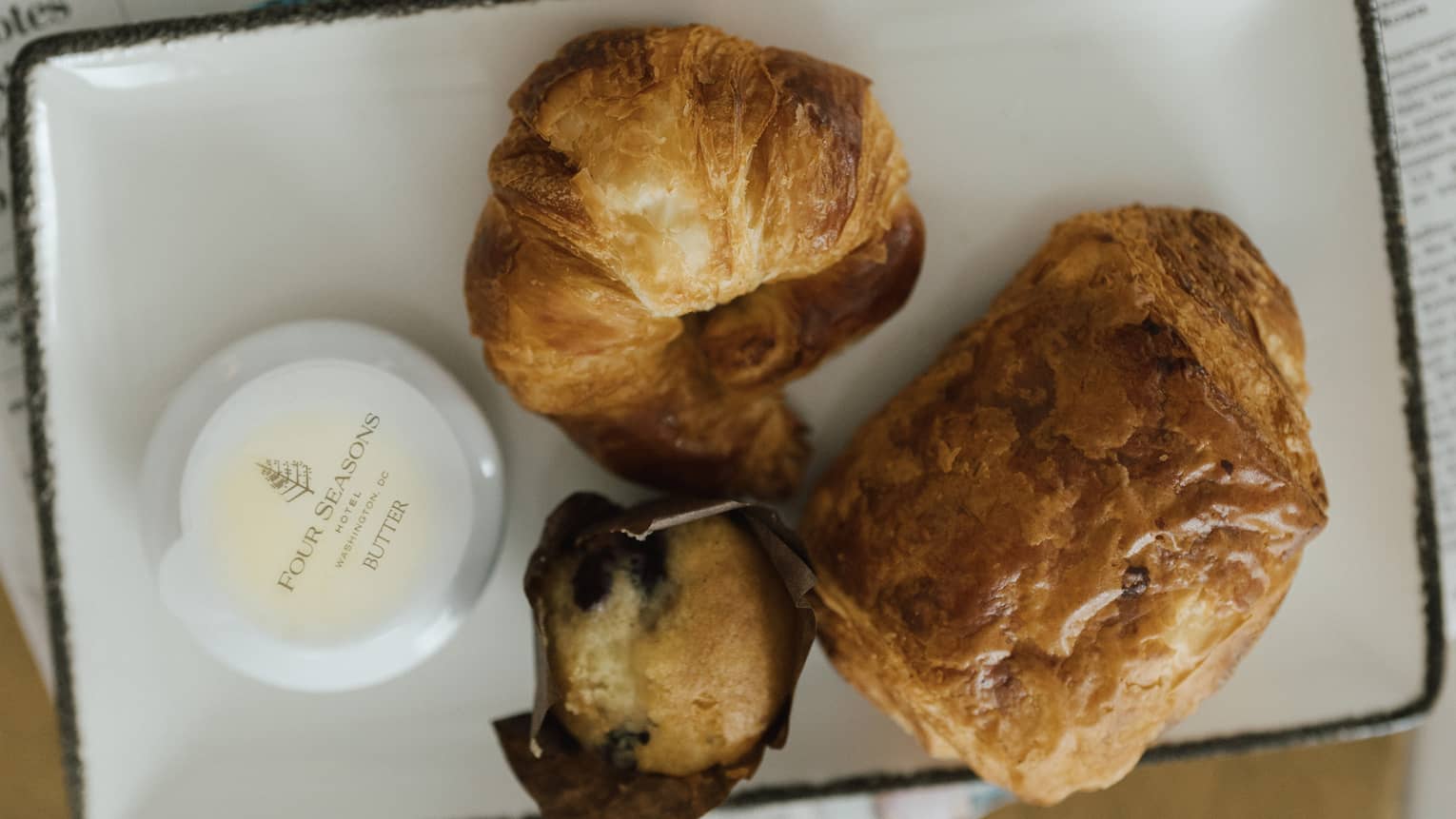 Pastries on a white tray resting on newspaper.
