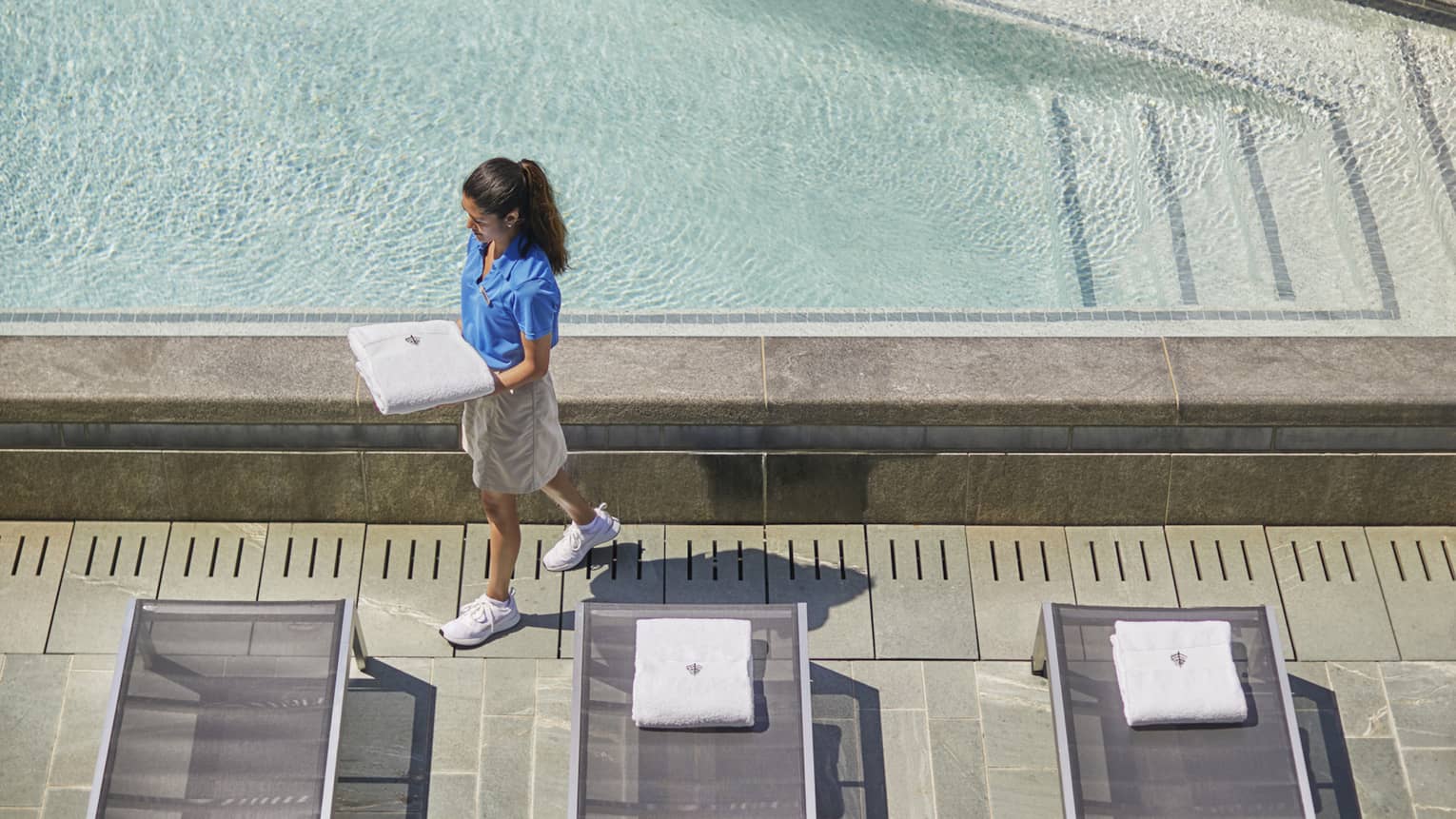 A hotel team member walking near a pool.