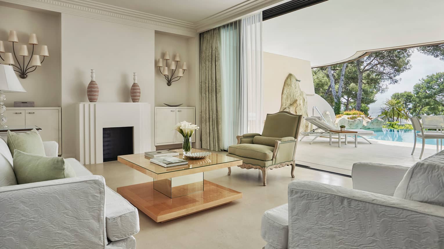 Pool Suite open-air living room with crisp white decor leading to sunny patio, pool