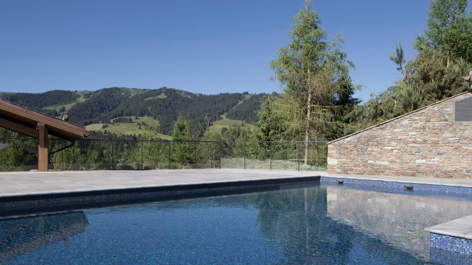 Heated outdoor pool under stone wall, green mountains