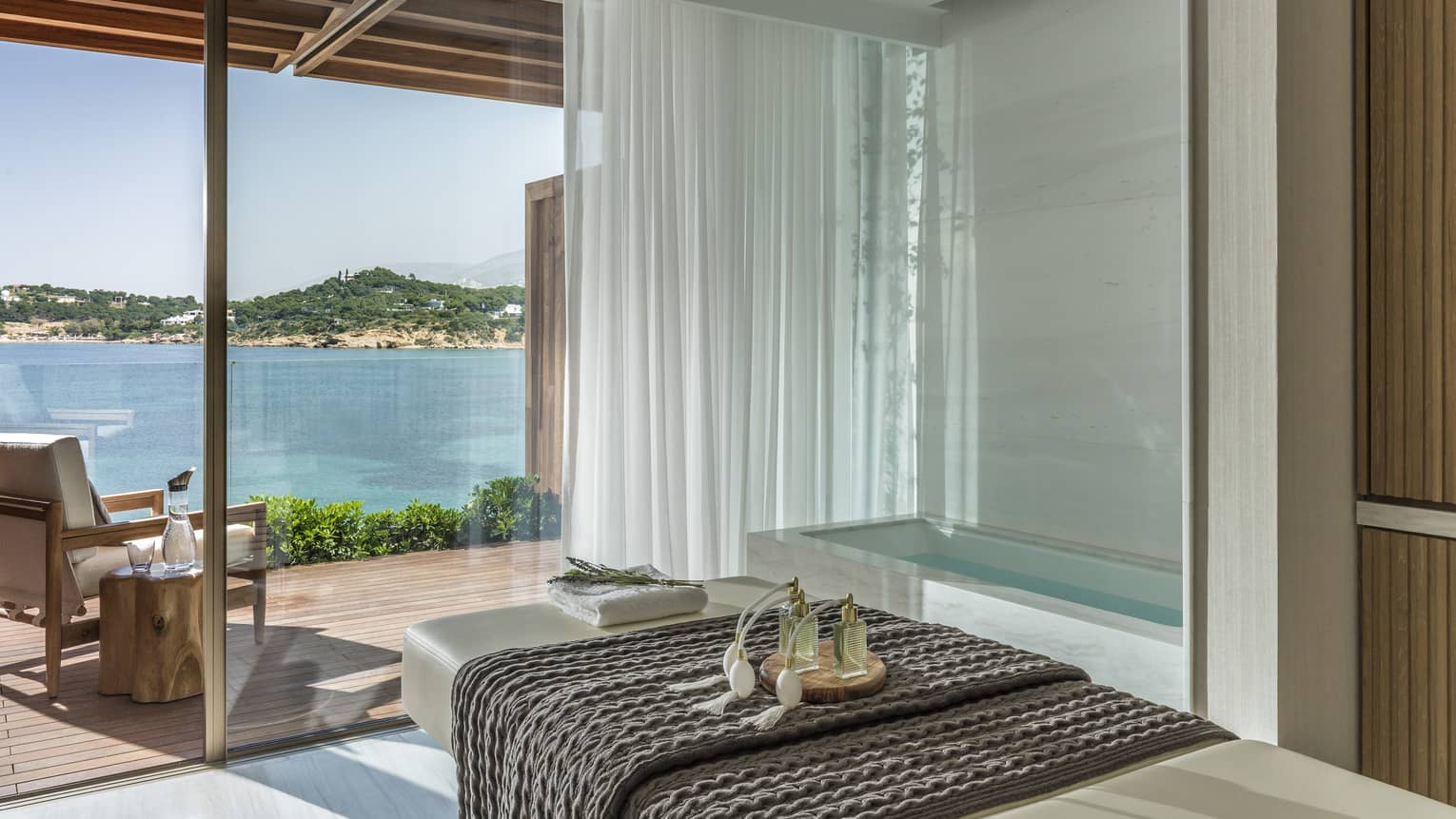 White spa table with dark blanket and water view from tall windows