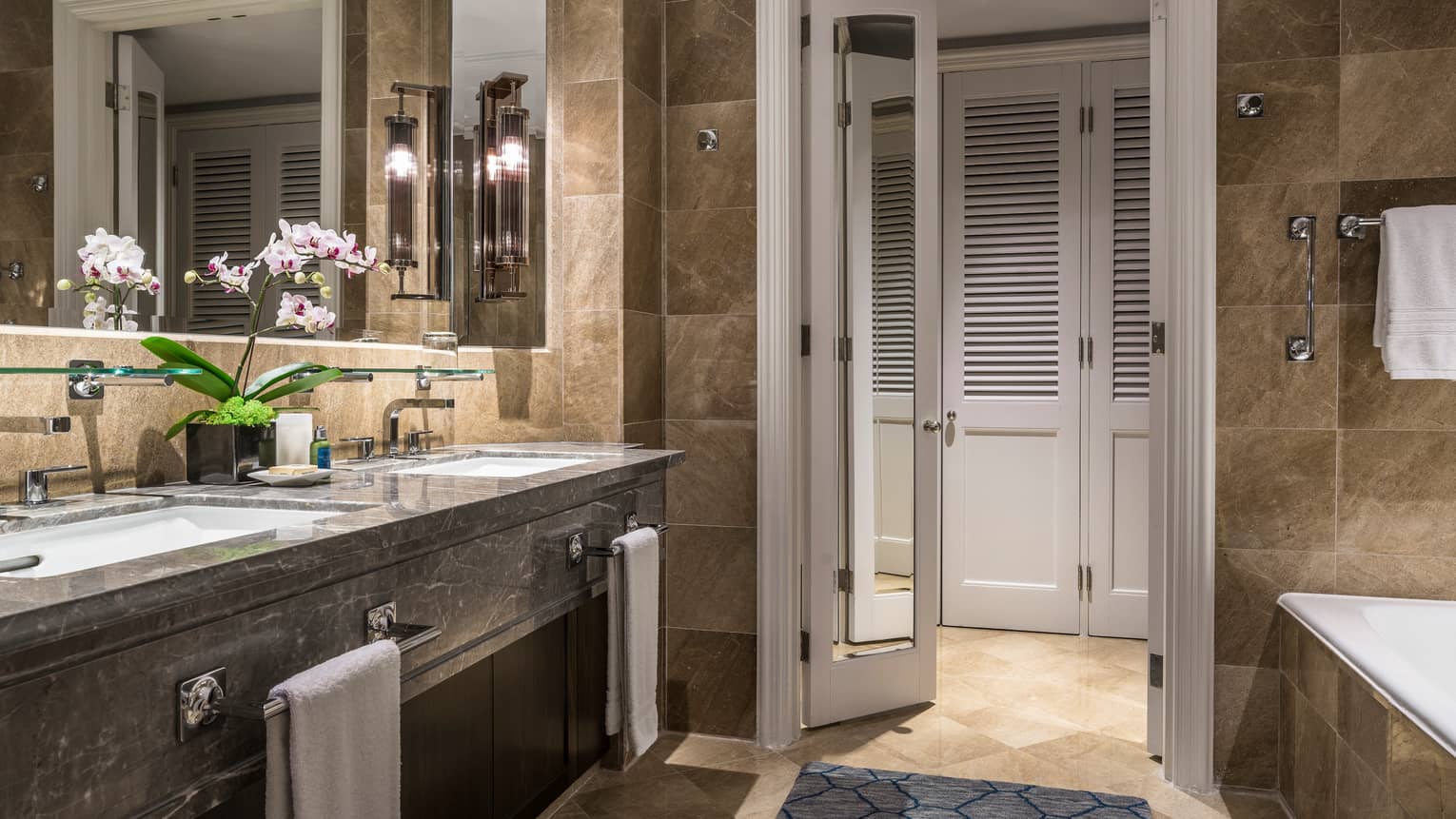 Luxurious bathroom featuring marble countertops, double sinks and elegant lighting.