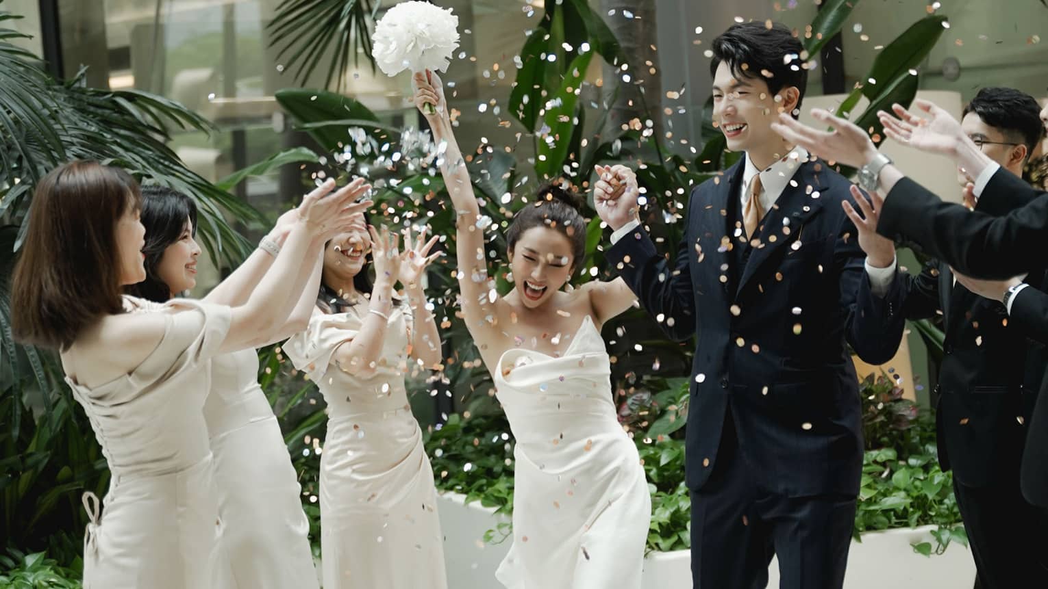 Wedding party members toss flower petals at newly married couple as they walk down the aisle