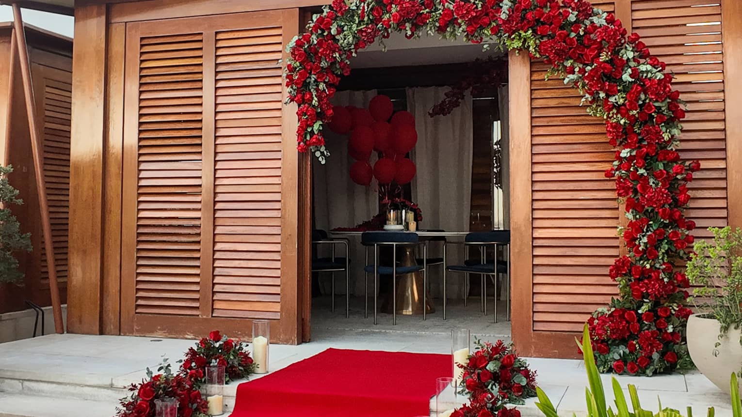 Poolside cabana entrance decorated with a red carpet lined with candles and a floral arch made of red roses