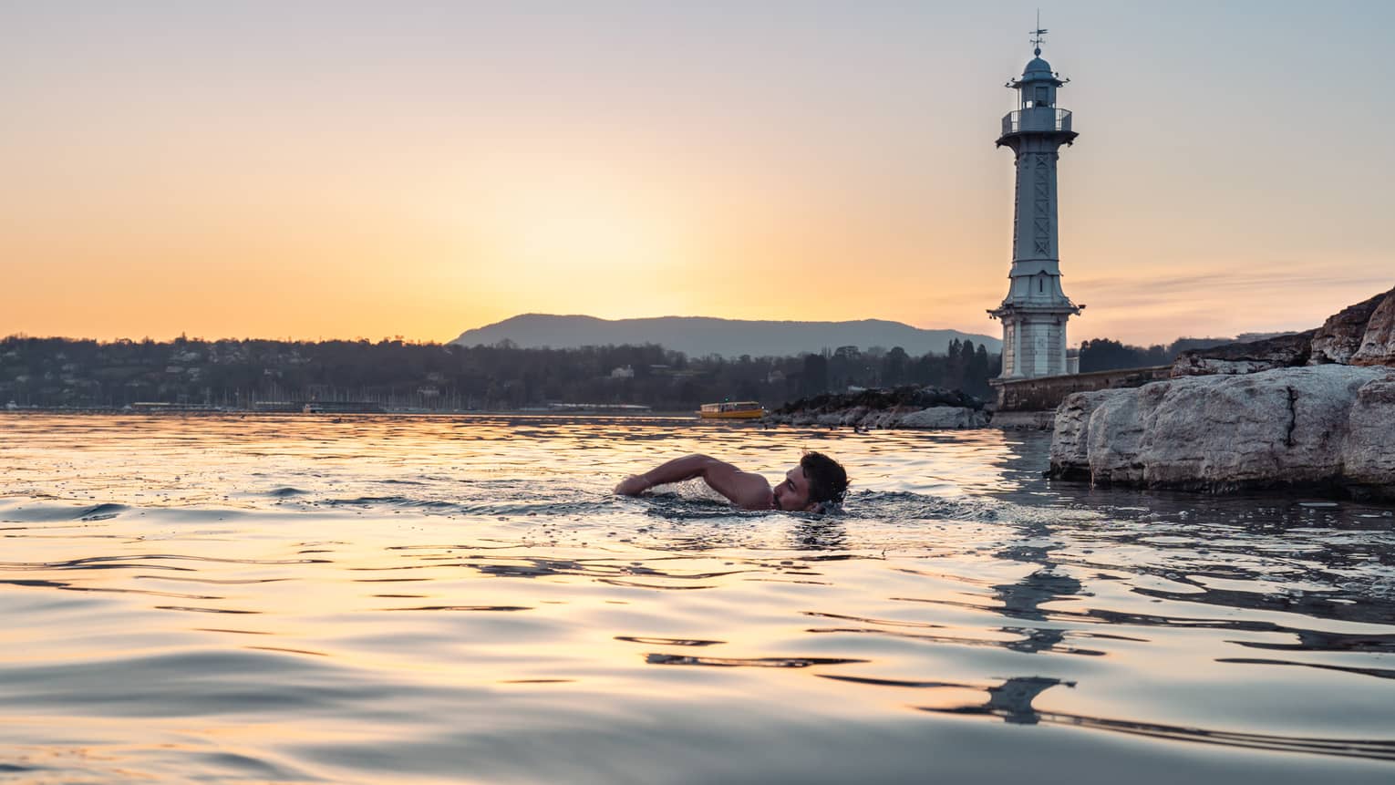 Person swimming in Lake Geneva at sunset
