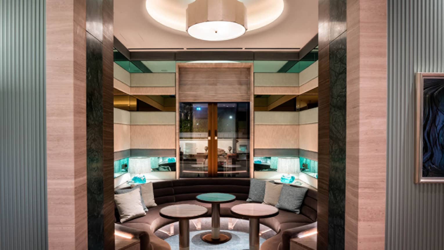 Intimate private dining space with dark brown curved banquette seating and three small round tables in centre
