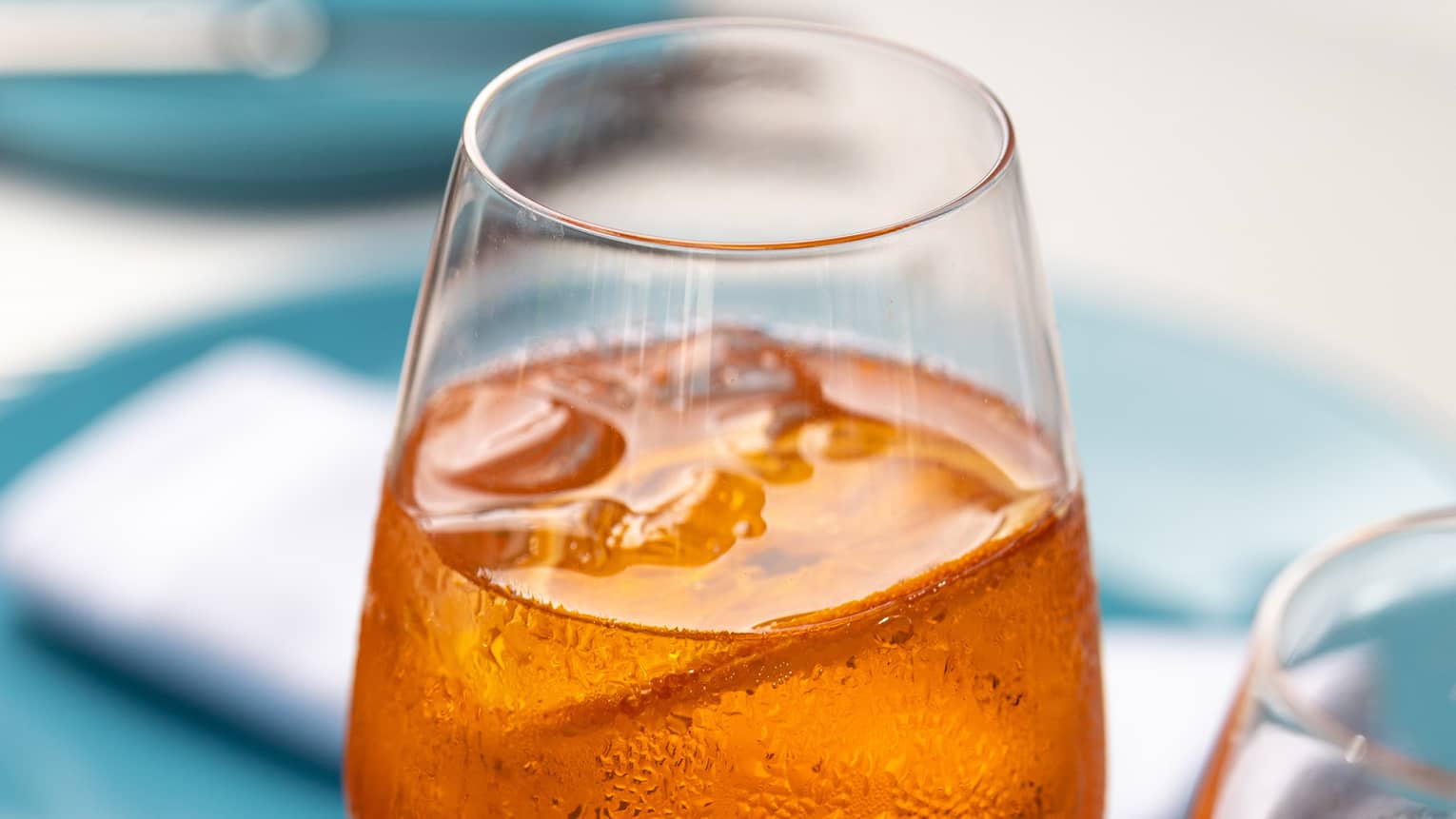 Two amber-coloured iced beverages in tall wine glasses