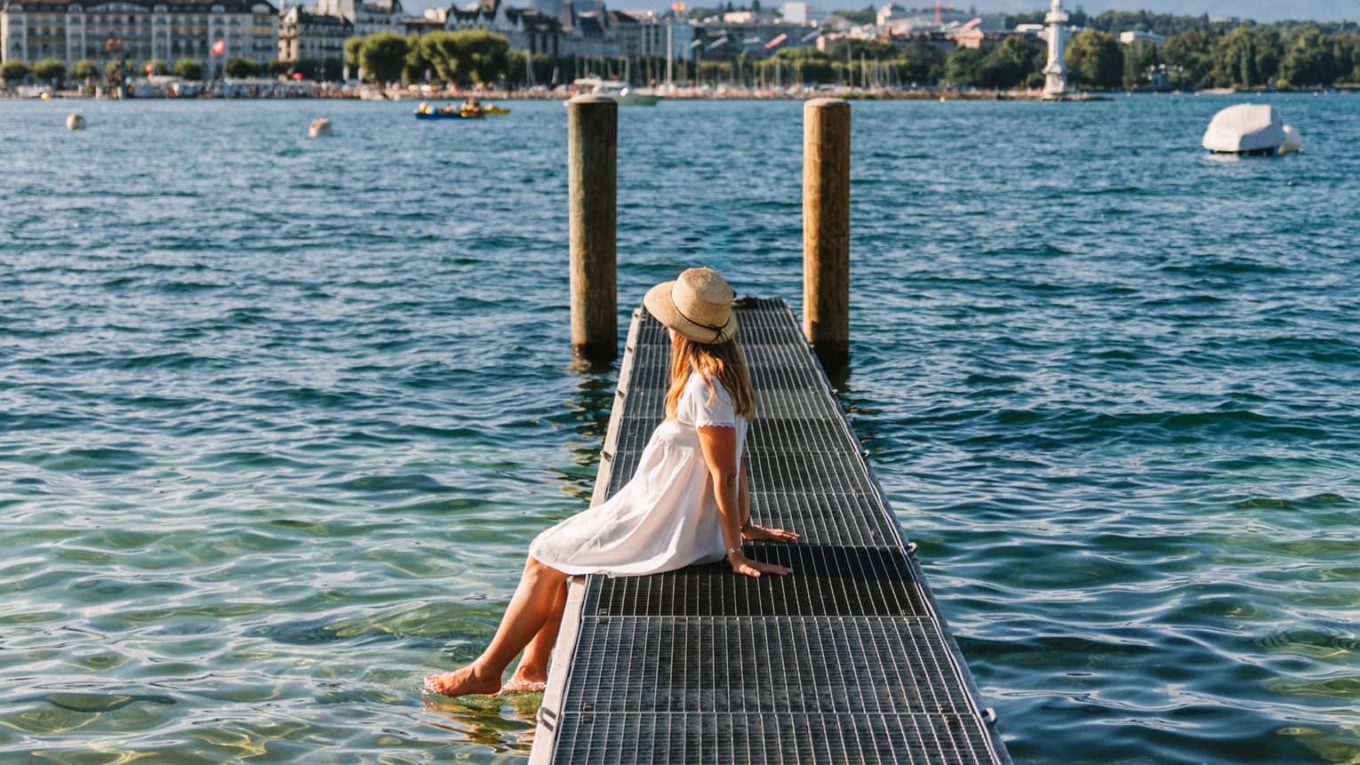 Child sitting on a narrow metal dock leading to two pylons in calm lake