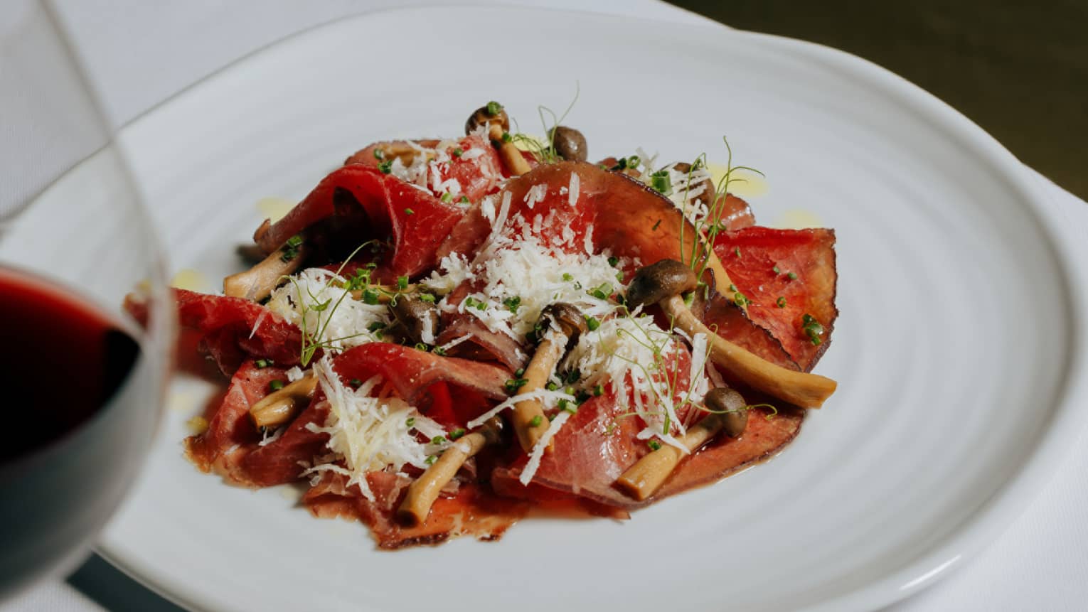 Wagyu beef carpaccio, soy mayo, pickled pioppini mushrooms and Parmigiano-Reggiano served on a white plate