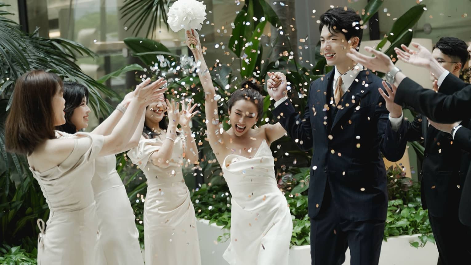 Wedding party members toss flower petals at newly married couple as they walk down the aisle
