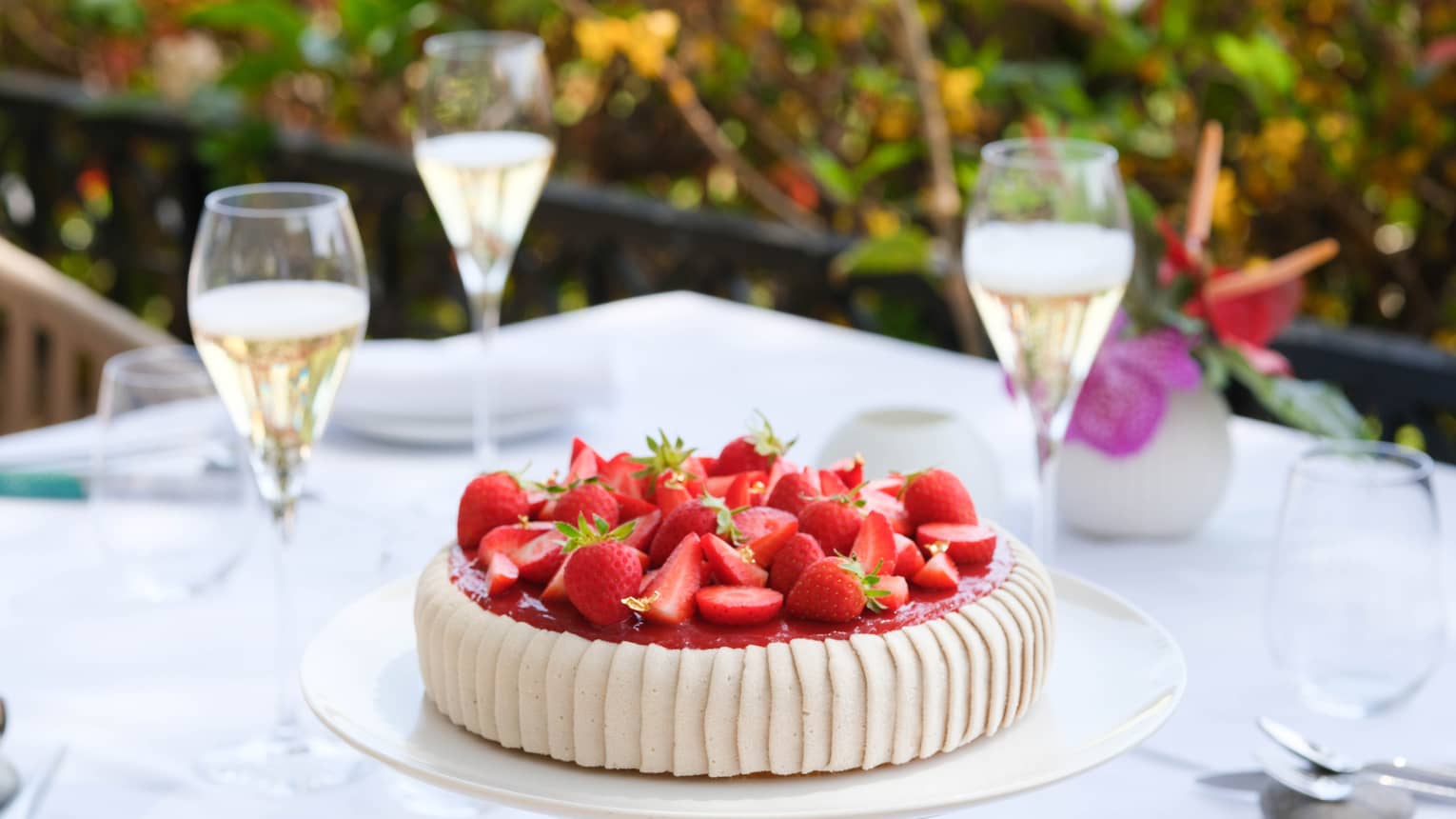 Round tart with vertically piped cream-coloured icing on sides and topped with fresh sliced strawberries