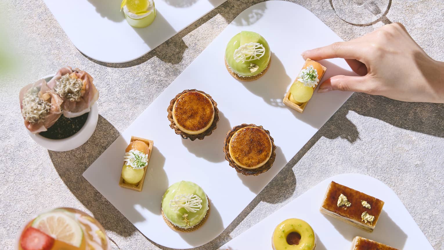 Platters of Afternoon Tea bites on a table, along with two drinks in stemmed glassware